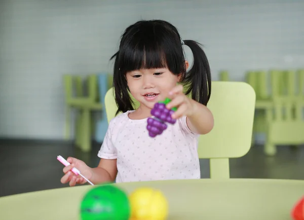 Enfant fille à la table joue des fruits artificiels dans la chambre des enfants . — Photo