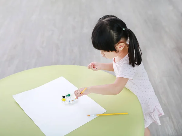 Παιδί κορίτσι ζωγραφική με το πινέλο και νερό χρώματα. Παιδί δραστηριότητες έννοια. — Φωτογραφία Αρχείου