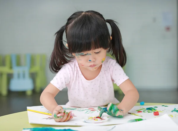 Child girl painting with paintbrush and water colors. Kid activities concept. Stock Image