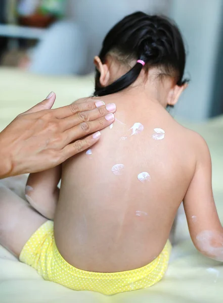 Мама намазывает крем на свою дочь дома . — стоковое фото