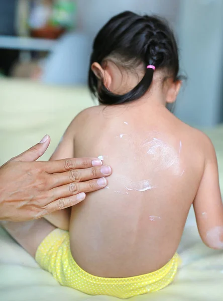 Мама намазывает крем на свою дочь дома . — стоковое фото