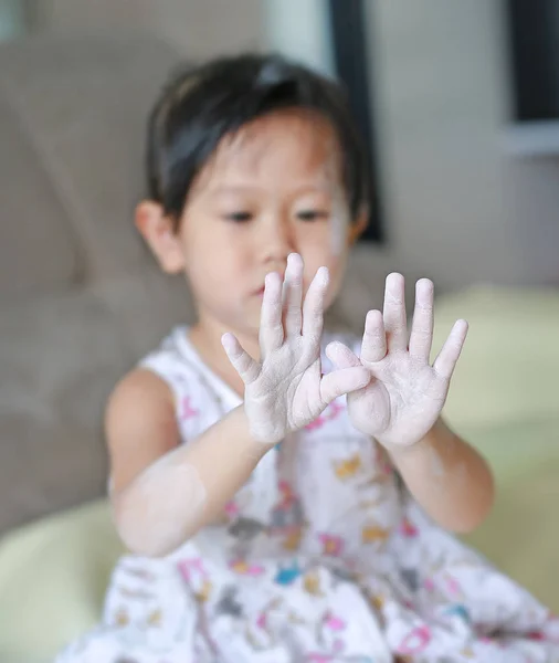 Милая маленькая девочка наносила детскую пудру на лицо и руку . — стоковое фото