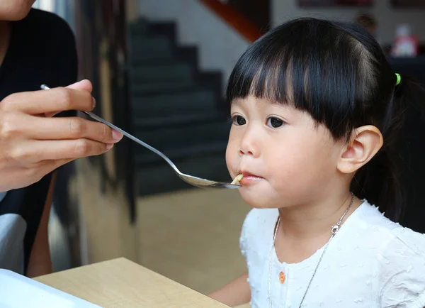 意大利面条饲勺子喂给她的孩子的母亲. — 图库照片