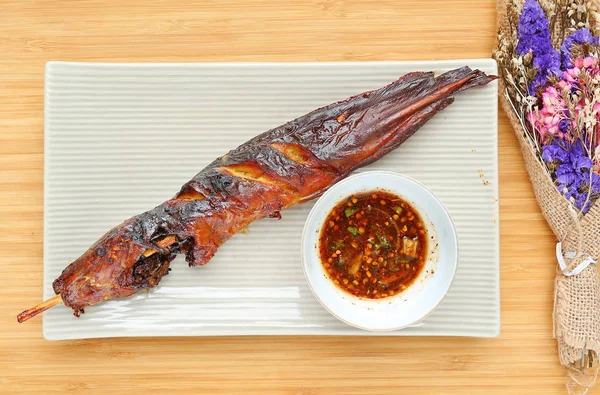 Bambu ahşap tahta karşı baharatlı sos ile kare plaka üzerinde ızgara yayın balığı — Stok fotoğraf