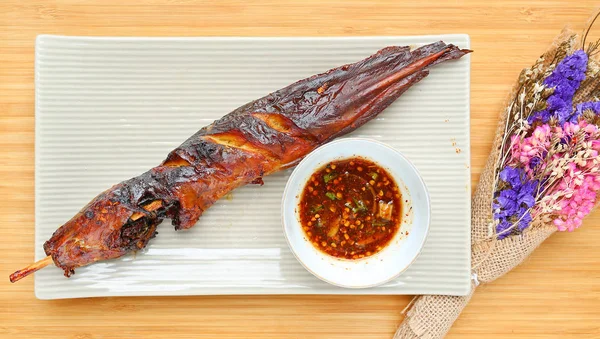 Bambu ahşap tahta karşı baharatlı sos ile kare plaka üzerinde ızgara yayın balığı — Stok fotoğraf