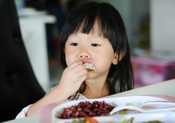 Lindo asiático chico chica edad acerca de 2 años viejo comer arroz por uno mismo — Foto de Stock
