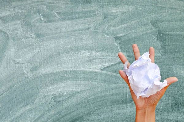 Mano tenendo carta stropicciata contro sfondo lavagna . — Foto Stock