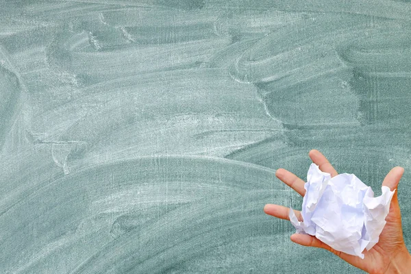 Mano tenendo carta stropicciata contro sfondo lavagna . — Foto Stock