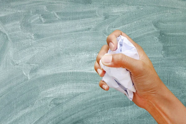 Mão segurando papel amassado contra fundo de quadro negro . — Fotografia de Stock