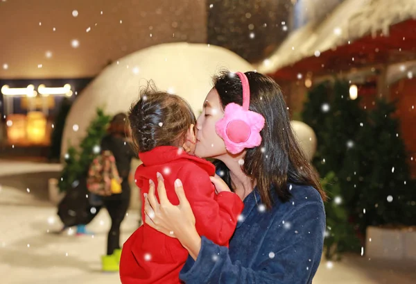 Мать целует свою дочь в снегу, в зимнее время . — стоковое фото