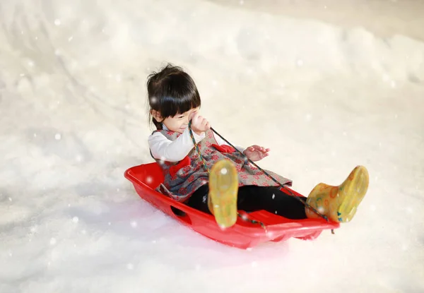 Blij meisje draagt een rood - grijze jas heeft een pret in de sneeuw — Stockfoto