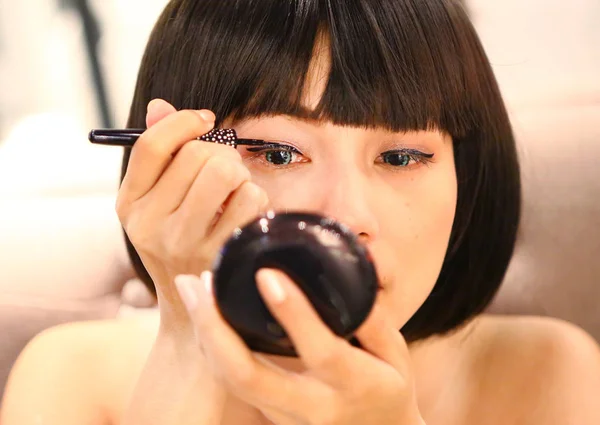 Portrait of beautiful woman making black eyeliner. Beauty Concept.