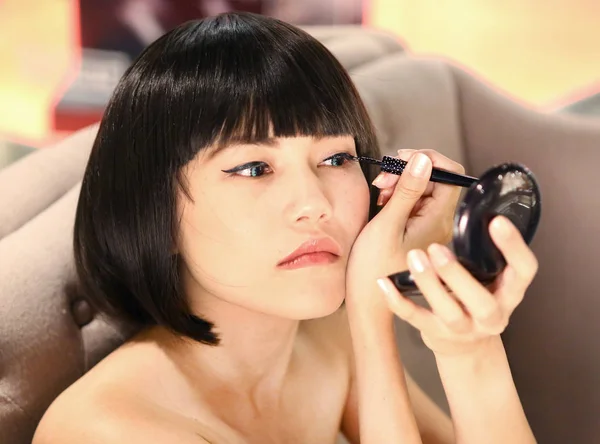 Portrait of beautiful woman making black eyeliner. Beauty Concept.