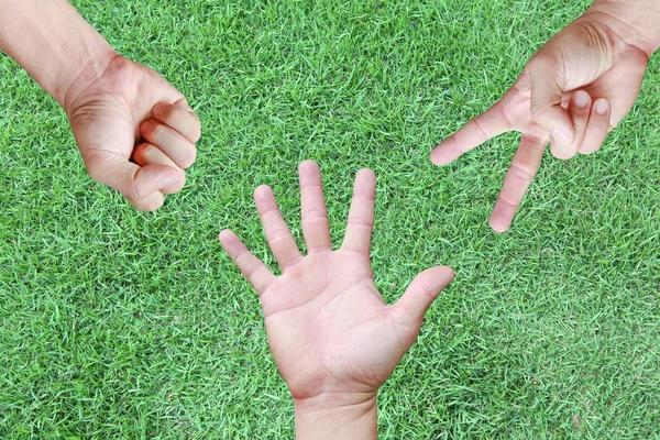 Close-up Rock ,Paper ,Scissors - hands on green grass background