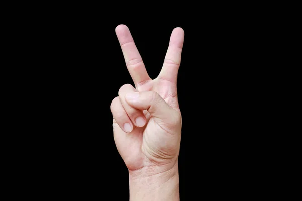 En hand visar signal sax på svart bakgrund. Hand med två fingrar upp i symbolen för fred eller seger. Även tecknet för bokstaven V i teckenspråk. — Stockfoto