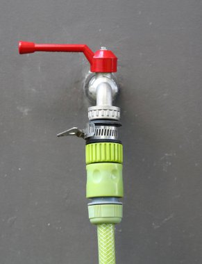 Yeşil kauçuk tüp gri duvar, musluk suyu