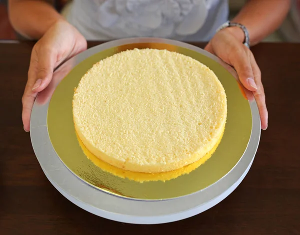 Torta de esponja en proceso en soporte sobre mesa de madera, pastel casero . —  Fotos de Stock