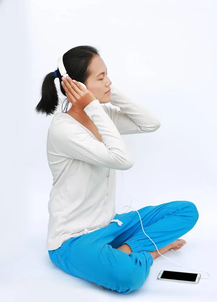 Jeune femme asiatique écouter de la musique dans les écouteurs sur fond blanc — Photo