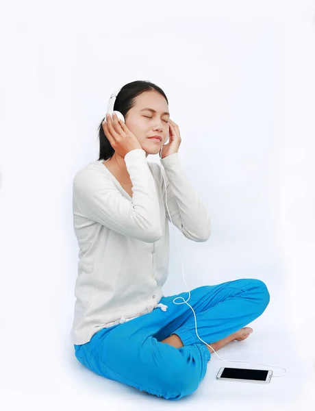 Jeune femme asiatique écouter de la musique dans les écouteurs sur fond blanc — Photo