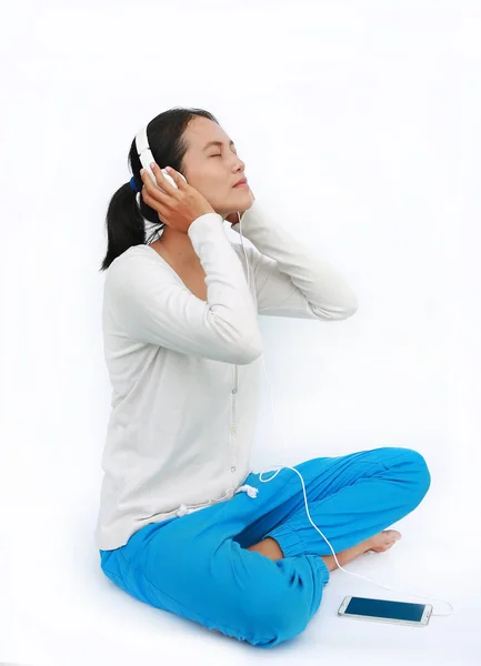 Jeune femme asiatique écouter de la musique dans les écouteurs sur fond blanc — Photo