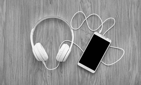 Headphones and smartphone on wooden background — Stock Photo, Image