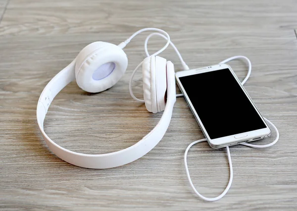 Headphones and smartphone on wooden background — Stock Photo, Image