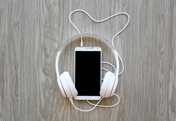 Headphones and smartphone on wooden background — Stock Photo, Image