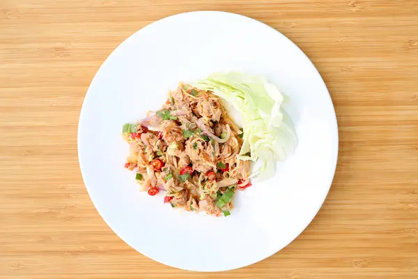 Ahşap arka plan üzerinde beyaz plaka baharatlı ton balığı salatası — Stok fotoğraf