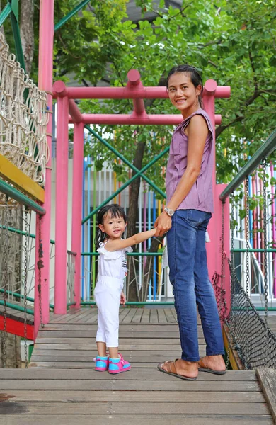 Mãe e seu filho menina andando em um playground ponte de madeira — Fotografia de Stock