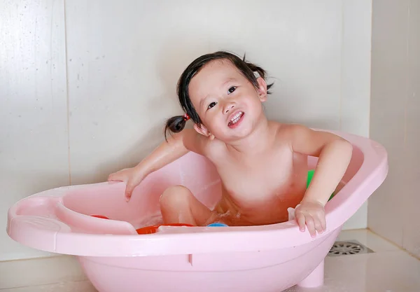 Menina banha-se em um banho rosa com um brinquedo — Fotografia de Stock