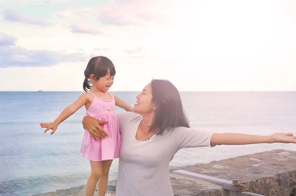 Mutlu sevgi dolu aile. Anne ve oynama ve deniz arka plan üzerinde akşam sarılma onun kızı çocuk kız — Stok fotoğraf