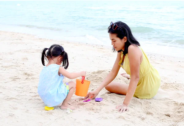 Счастливая семья. Мать и дочь девочка играют в песок с животным блоком, образующимся на пляже — стоковое фото