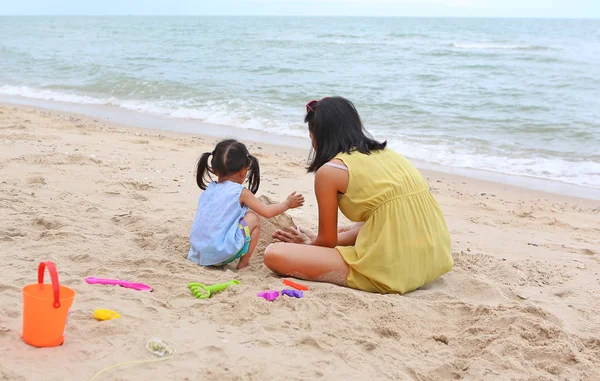 Szczęśliwy, kochającą rodzinę. Matka i jej córka dziecko dziewczynka grający piasek z blok zwierząt na plaży — Zdjęcie stockowe