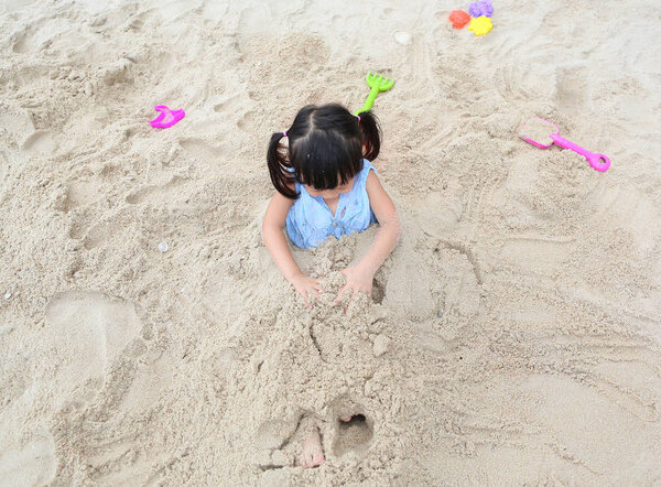 Милая девочка играет в песок на пляже
