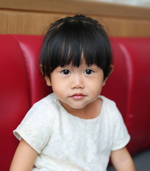 Retrato de um pequeno bebê asiático menina no sofá vermelho — Fotografia de Stock