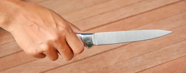 Ein Messer, das mit den Händen gegen Bretterholz gehalten wird — Stockfoto