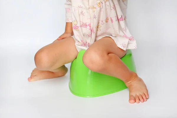 Маленькая девочка сидит на туалетном горшок на белом фоне — стоковое фото