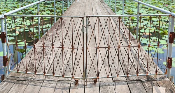Jembatan kayu dengan gerbang di bunga bakung — Stok Foto
