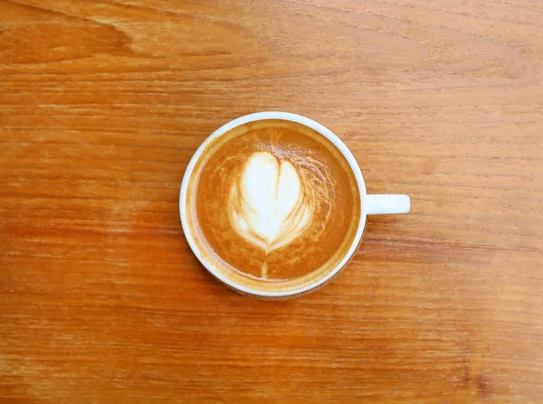 Bovenaanzicht van een kopje koffie met hart patroon in een witte beker op houten achtergrond, latte art — Stockfoto