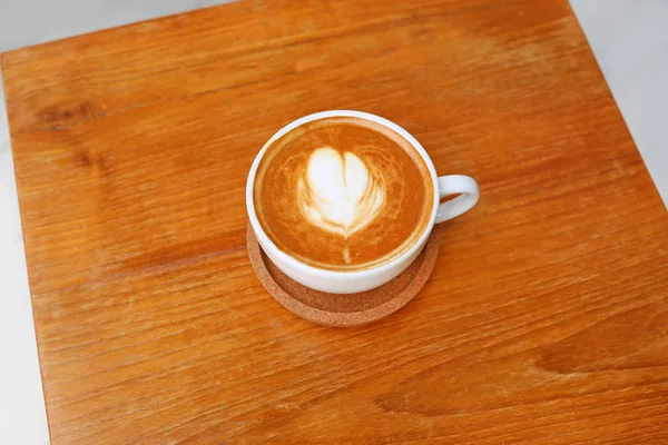 Café com padrão de coração em uma xícara branca em fundo de madeira, arte latte — Fotografia de Stock