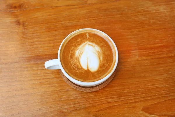 Кофе с рисунком сердца в белой чашке на деревянном фоне, латте искусства — стоковое фото