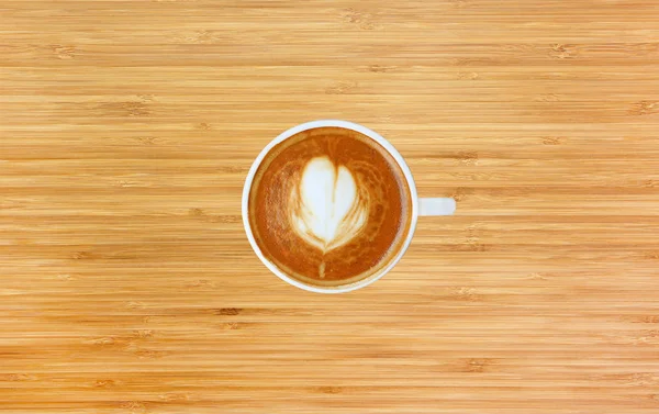 Bovenaanzicht van een kopje koffie met hart patroon in een witte beker op houten achtergrond, latte art — Stockfoto