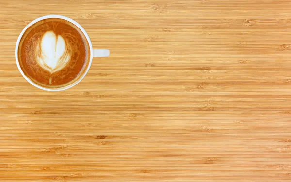 Vista superior de um café com padrão de coração em uma xícara branca em fundo de madeira, arte latte — Fotografia de Stock