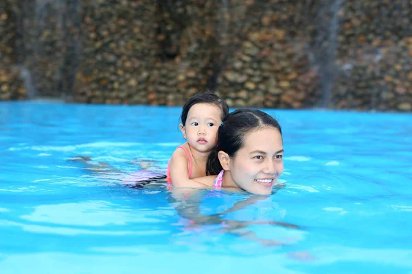 Красивая маленькая девочка с матерью, играющей в бассейне на открытом воздухе — стоковое фото