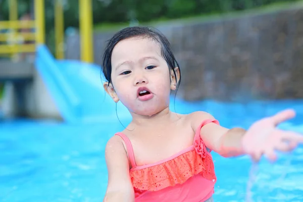 Красивая маленькая девочка играет в бассейне на открытом воздухе — стоковое фото