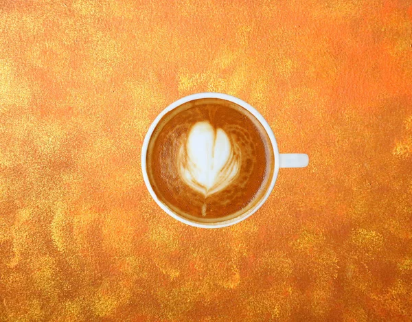 Bovenaanzicht van een kopje koffie met hart patroon in een witte beker op goud patroon achtergrond, Latte art koffie — Stockfoto