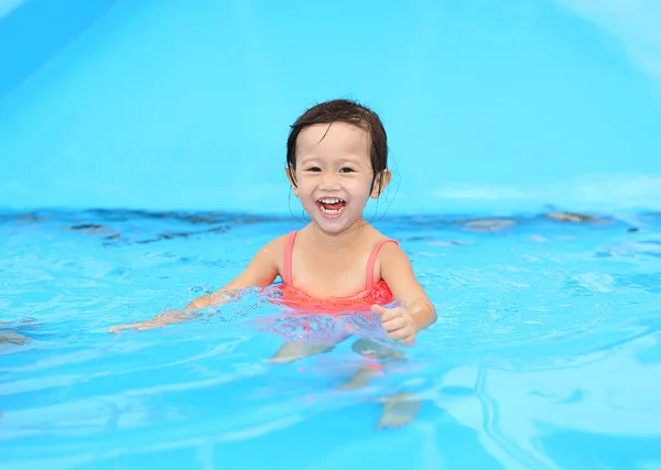 Красивая маленькая девочка играет в бассейне на открытом воздухе — стоковое фото