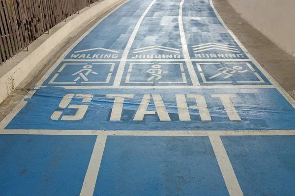 Punto de inicio, pista de atletismo azul con señal de marcha, trotar o correr, concepto ligero para el éxito —  Fotos de Stock