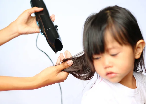 Madre asciugando i capelli della sua bambina su sfondo bianco — Foto Stock