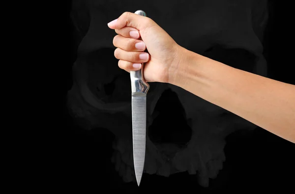 Hand hält ein Messer bereit, um gegen den Schädel auf schwarzem Hintergrund zu schlagen — Stockfoto